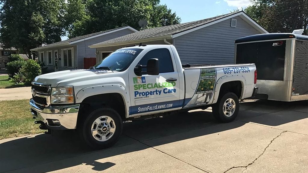 Specialized Property Care truck parked in residential area, showcasing services for lawn care and snow removal, with contact information visible on vehicle.