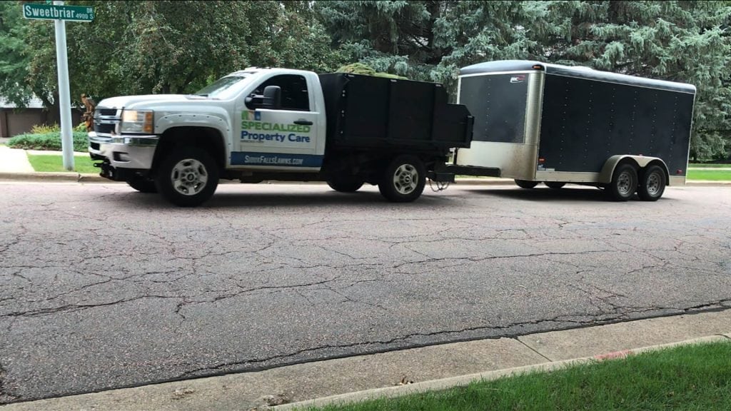 Specialized Property Care truck with trailer on Sweetbriar Drive in Sioux Falls, emphasizing reliable lawn and property care services.