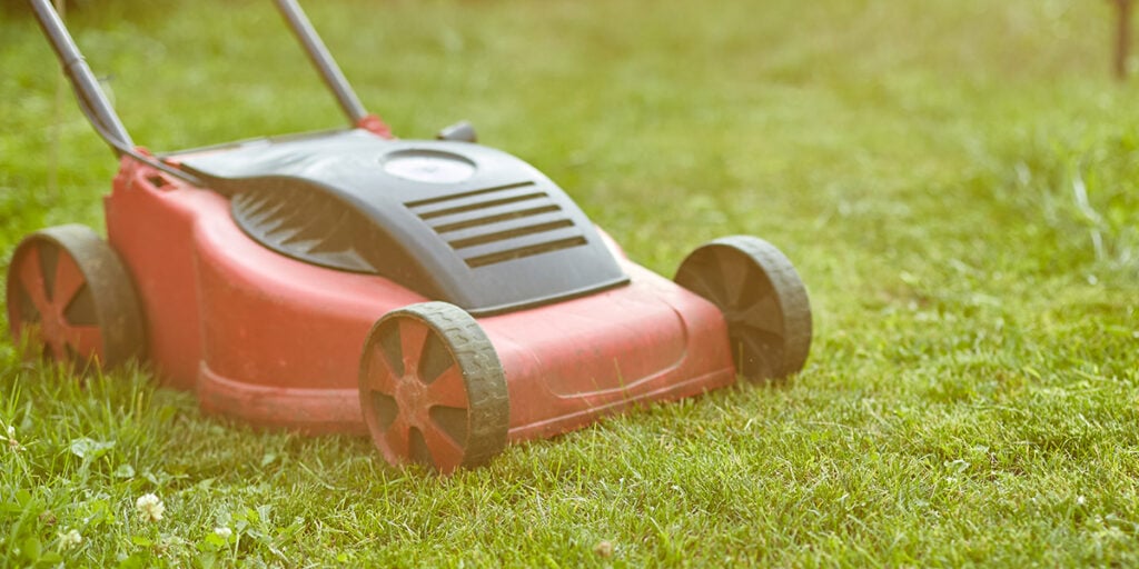 Lawn mower on green grass, highlighting winter lawn care and maintenance for healthy grass growth in Sioux Falls, SD.