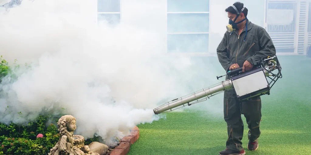 Professional pest control technician applying mosquito treatment in residential yard, surrounded by outdoor greenery and a decorative statue, emphasizing effective mosquito control to enhance outdoor enjoyment and safety.