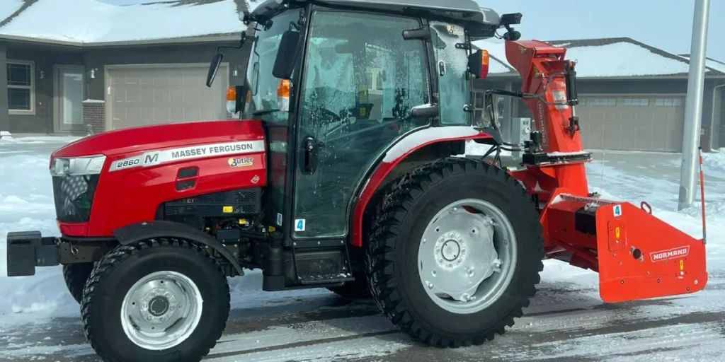 Massey Ferguson tractor equipped with a snowblower attachment, parked on a snowy driveway in front of a residential property, illustrating winter snow removal services offered by Specialized Property Care.
